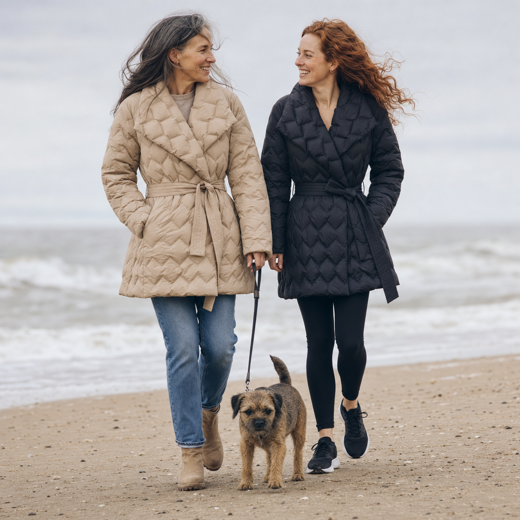 De donsjas in zandbeige en zwart tijdens een strandwandeling